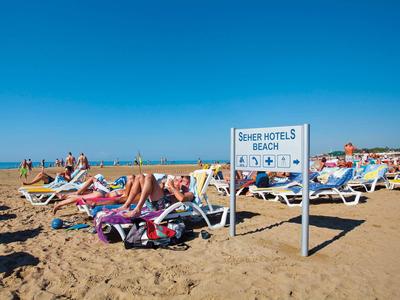 Strand mit Liegestühlen und Schild "Senior Hotels Beach" unter klarem blauem Himmel.