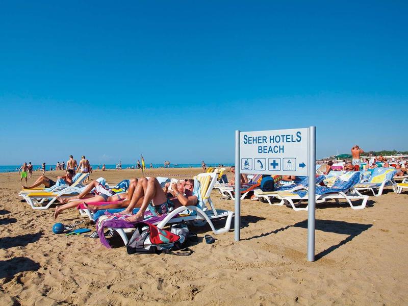 Children playing on a colorful playground with slides and swings on a clear day.