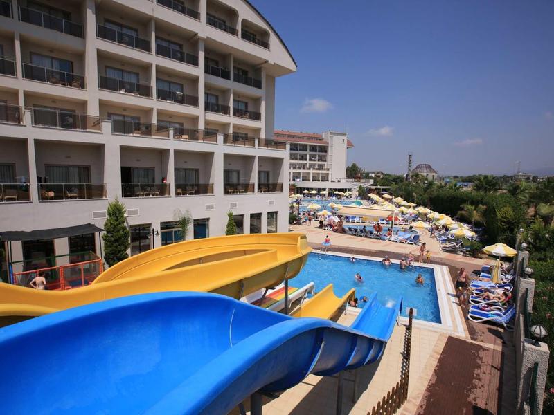 Hotel with water slides and pool area with sun loungers and umbrellas.