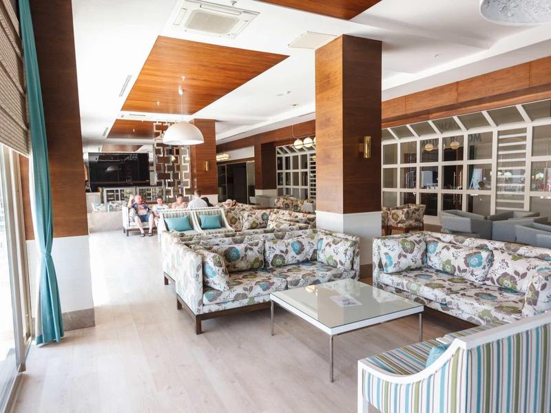 Bright lounge area with modern floral sofas and large windows in a hotel.