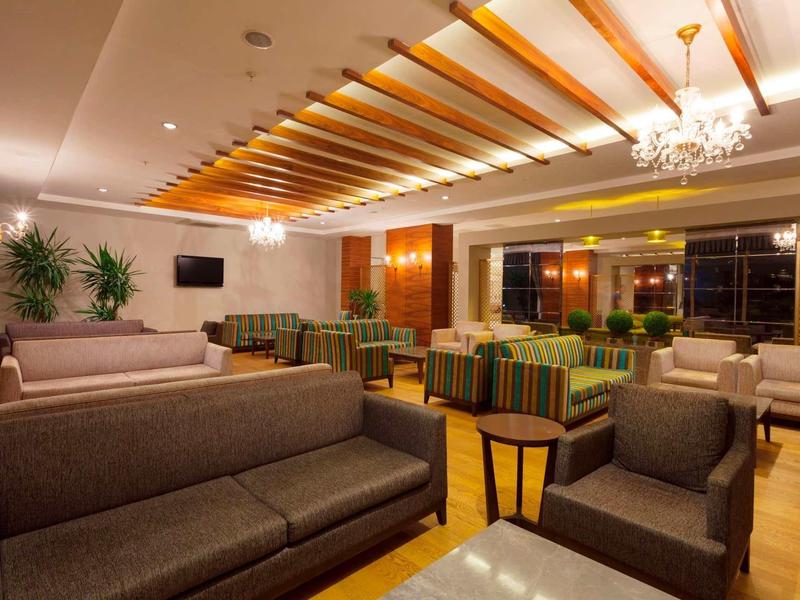 Spacious hotel lounge area with multiple sofas, armchairs, and elegant ceiling lights.