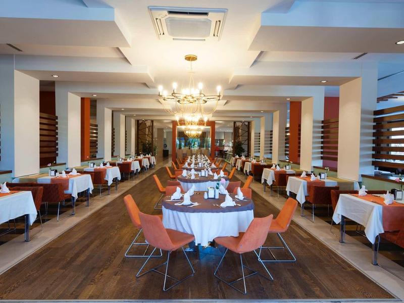 Elegant restaurant with round set tables and orange chairs in a modern setting.