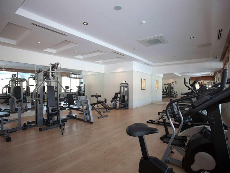 Modern fitness equipment in a bright, spacious hotel gym with wooden flooring.