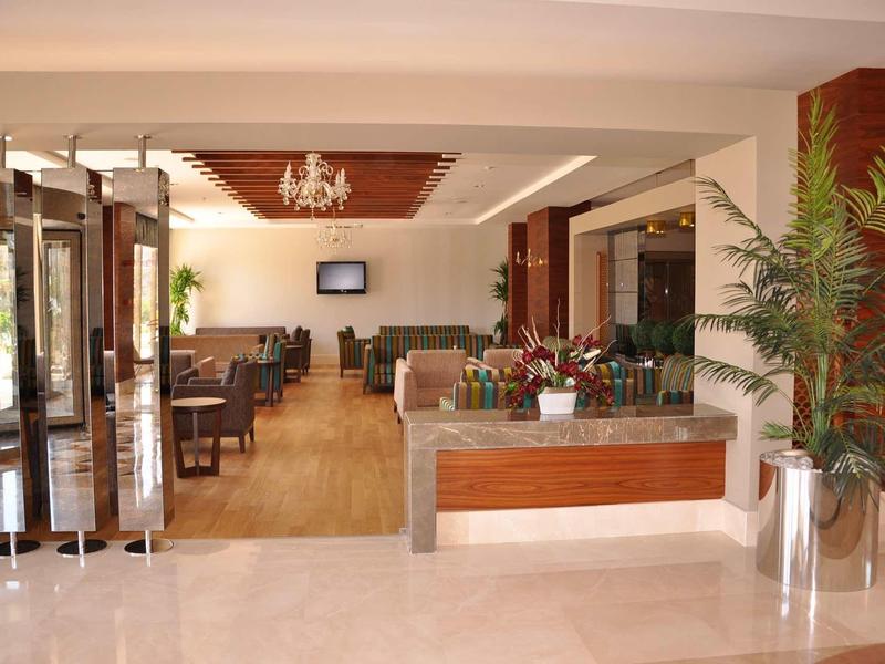 Bright hotel lobby with reception desk, seating area, and large plants