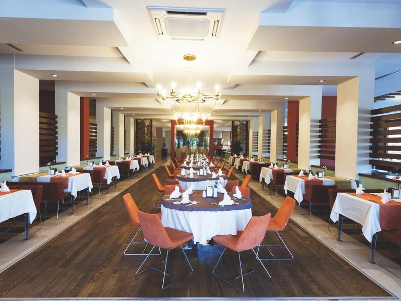 Elegant restaurant with set tables and chairs on wooden floor under ceiling lights.