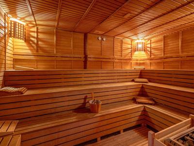 Innenraum einer Holzsauna mit mehrstufigen Sitzbänken und gedämpftem Licht an der Wand.