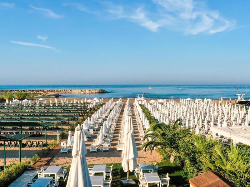 Uitzicht op een strandgedeelte met veel parasols en ligstoelen aan zee.