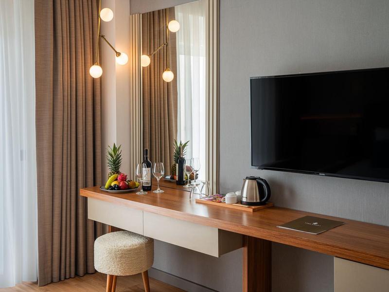 Modern bureau in hotelkamer met tv, spiegel en kleine stukjes fruit.