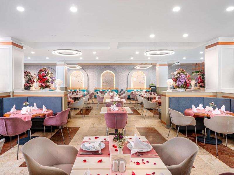 Elegant, licht restaurant met gedekte tafels en roze stoelen.