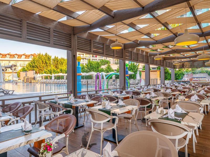 Groot overdekt terras met veel tafels en stoelen in een hotelrestaurant.