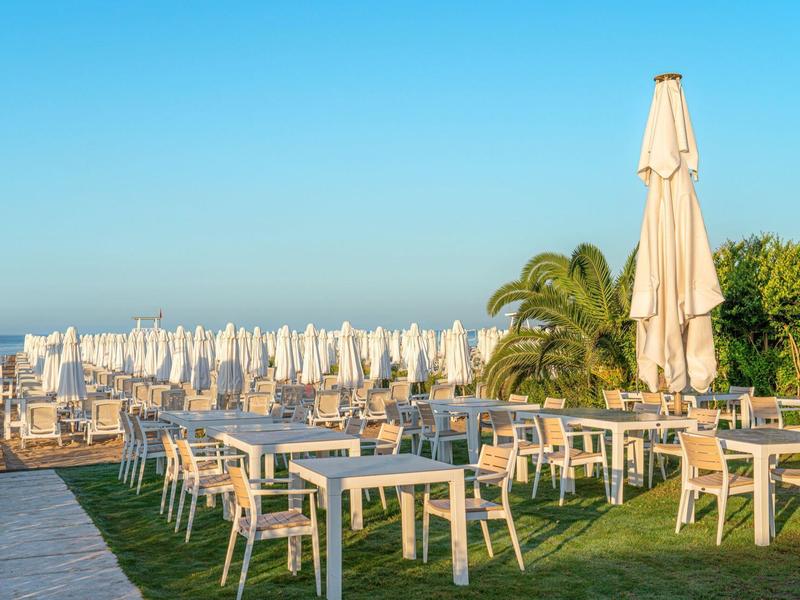 Leeg buitenterras met tafels en stoelen naast gesloten parasols in de vroege ochtend.