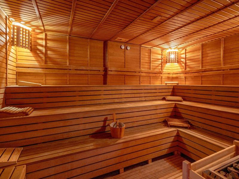 Houten sauna met meerdere niveaus zitbanken en zachte verlichting aan de muren.
