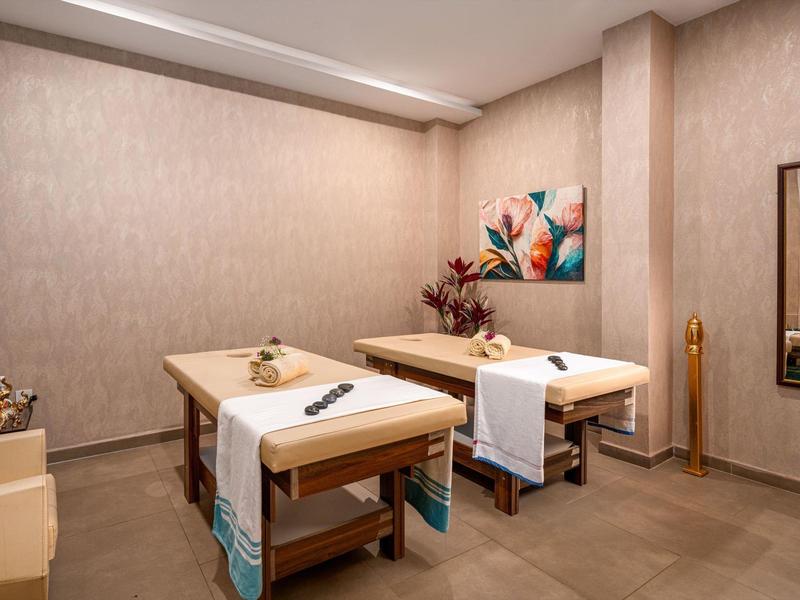 Rustige behandelkamer met twee massagetafels, zachte handdoeken en kalmerende decoratie.