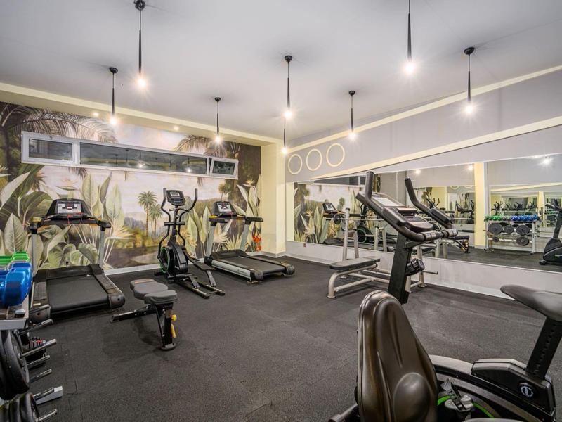 Moderne fitnessruimte met verschillende trainingsapparaten en wandspiegels.