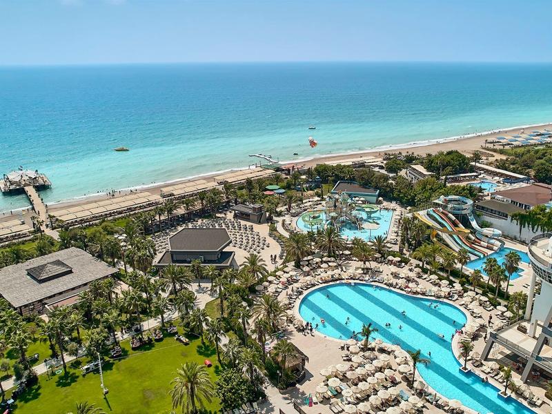 Vue sur la station avec piscines, plage et mer par une journée ensoleillée.