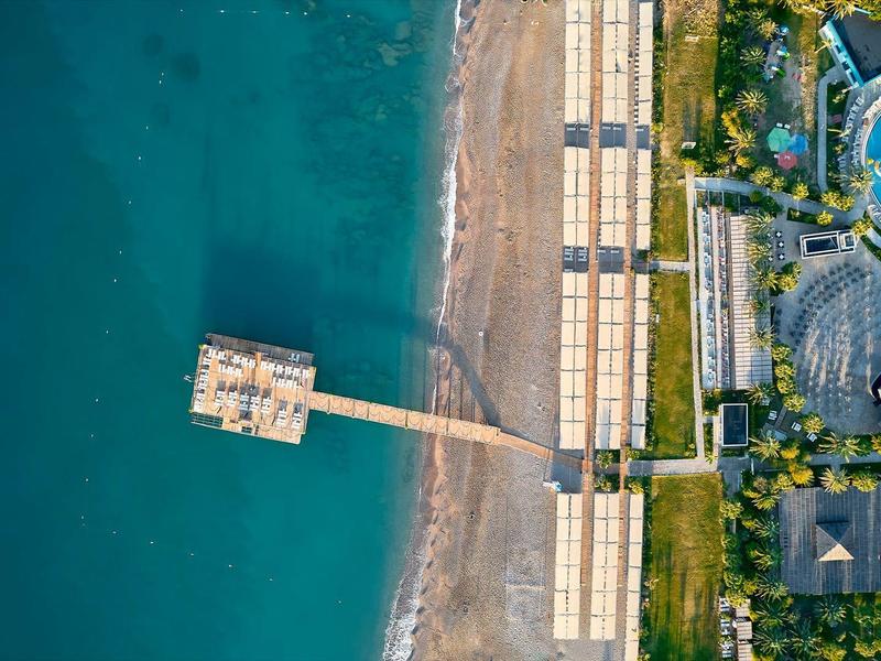 Vue aérienne d'une plage avec une jetée et une piscine d'hôtel adjacente.