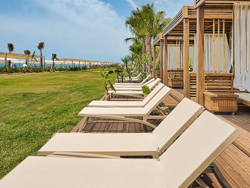 Chaises longues et pavillons en bois sur l'herbe près de la plage par temps clair.
