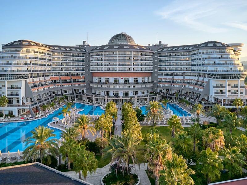Grand hôtel avec plusieurs piscines et jardins verts au coucher du soleil