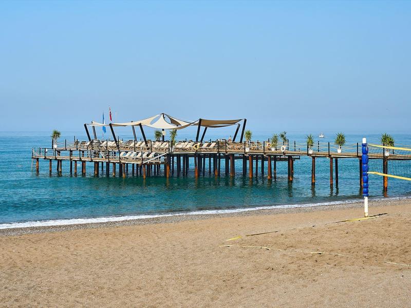 Une jetée en bois avec pare-soleil sur la plage calme avec ciel bleu et mer.