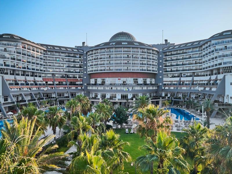 Hôtel moderne à l'architecture courbée, entouré de verdure tropicale et d'une piscine.