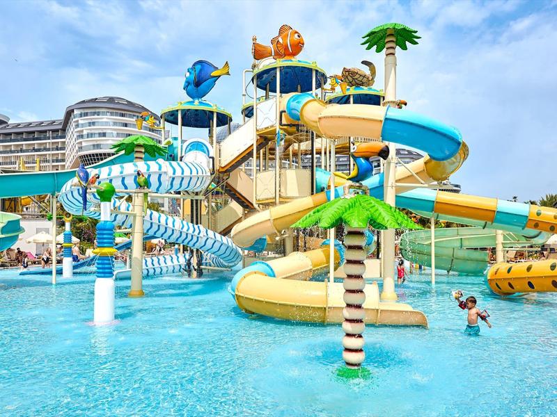 Aire de jeux aquatique colorée avec toboggans et bassin sous ciel bleu dans une station de vacances.