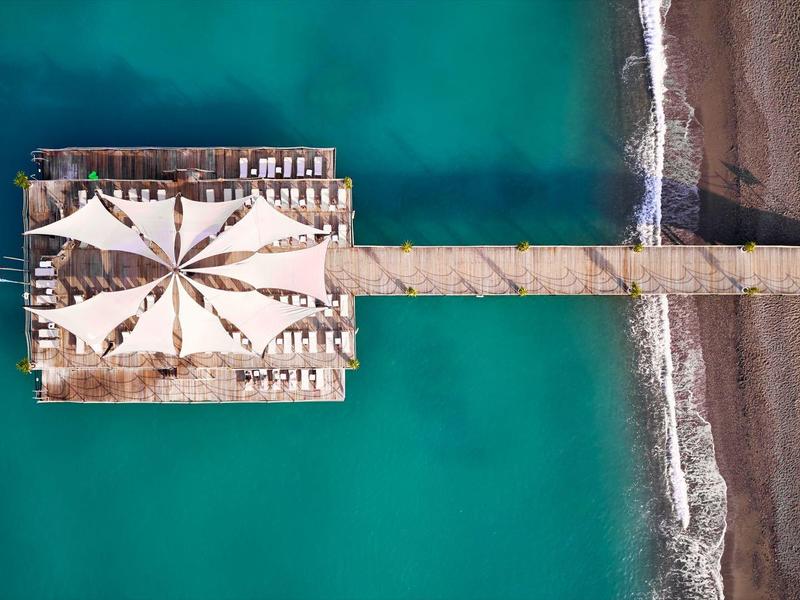Vue aérienne d'une longue jetée avec parasols s'étendant dans la mer turquoise