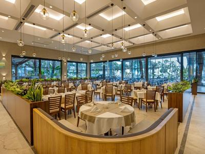 Ristorante elegante con tavoli, sedie e grandi finestre che offrono molta luce naturale.