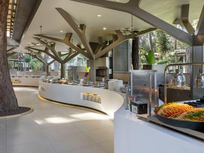 Modern gestalteter, heller Frühstücksbereich in einem Hotel mit Buffetstation und Sitzgelegenheiten.