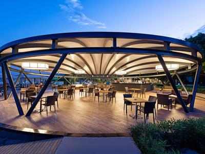 Modernes, offenes Restaurant mit beleuchtetem Zeltdach und Tischen im Außenbereich bei Dämmerung