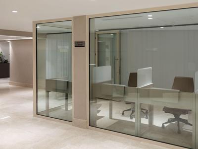 Moderner Bürobereich mit Glaswänden und Stühlen in einem Hotel- oder Geschäftsgebäude.