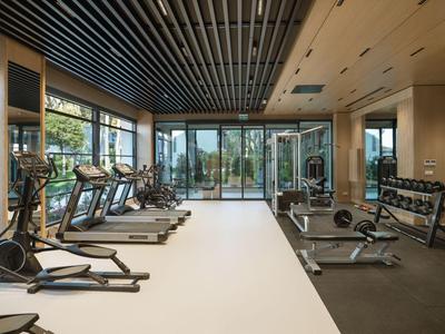 Moderner Fitnessraum mit Laufbändern, Hanteln und großen Fenstern mit Blick nach draußen.