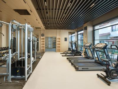 Moderner Fitnessraum mit Geräten wie Laufbändern und Hanteln in einem Hotel.