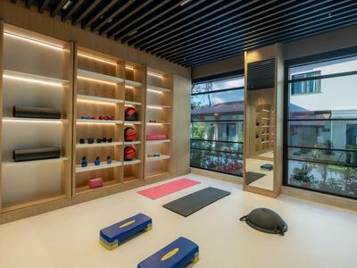 Moderner Fitnessraum mit Yogamatten, Balance-Geräten und Wandregalen mit Sportzubehör.