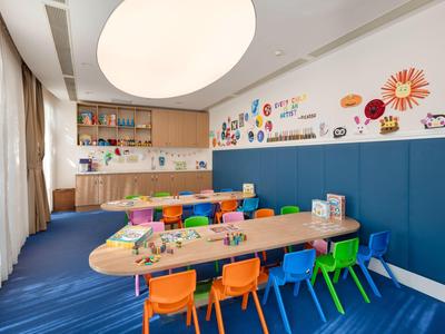 Bunter Kinderraum mit Tischen, Stühlen und Wanddekoration in einem Hotel.