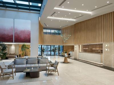Moderner Hotellobby mit bequemen Sitzgelegenheiten, großer Fensterfront und hellem Holzdekor.