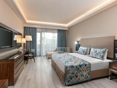 Modern eingerichtetes Hotelzimmer mit Doppelbett, Sitzbereich und großem Fenster mit Blick.