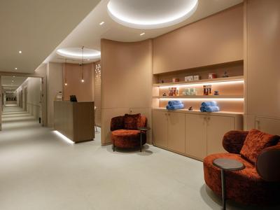 Eleganter Hotelflur mit sanfter Beleuchtung, gemütlichen Sesseln und stilvollen Wandregalen entlang der Wand.