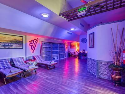 Moderner Wellnessbereich mit Holzliegen, bunter Beleuchtung und hellblauen Wänden.