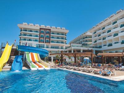 Hotel z basenem, wieloma zjeżdżalniami wodnymi i leżakami pod jasnym, niebieskim niebem.