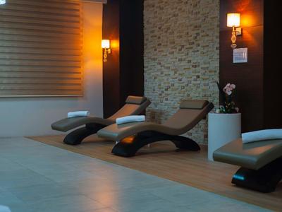 Słabo oświetlony pokój wypoczynkowy z trzema nowoczesnymi leżakami i ciepłymi lampami ściennymi.