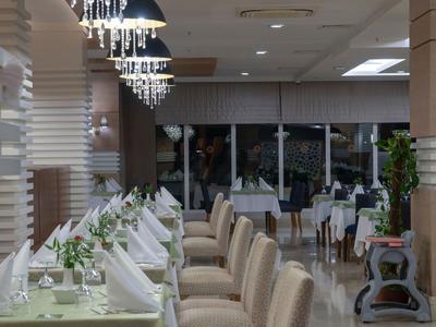 Elegancka restauracja hotelowa z nakrytymi stołami i tapicerowanymi krzesłami.