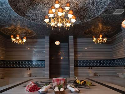 Luksusowy turecki hammam z mozaikowymi wzorami, żyrandolami i zadbanymi akcesoriami spa.