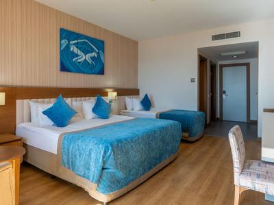 Modern hotelkamer met groot bed, blauwe accenten en houten vloer.