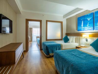 Hotelkamer met twee bedden, houten vloer, twee blauwe kussens en nautische wanddecoratie.