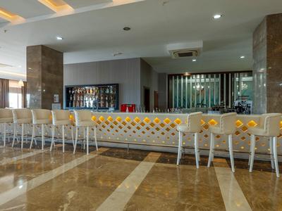 Moderne hotelbar met lange toog en witte barkrukken op een marmeren vloer.