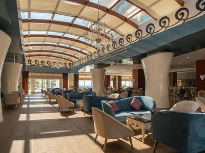Heldere hotel lounge met grote ramen, zithoeken en modern interieur.