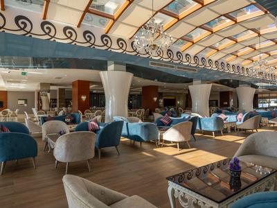 Licht hotelrestaurant met moderne fauteuils en tafels onder een glazen dak.