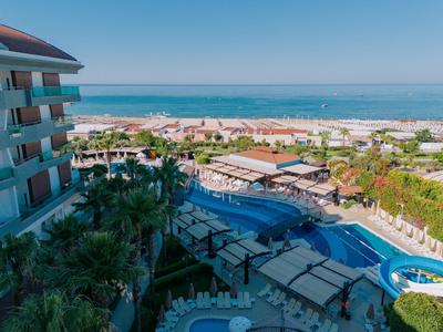 Hotel met buitenzwembad en uitzicht op het strand en de zee onder een heldere lucht.