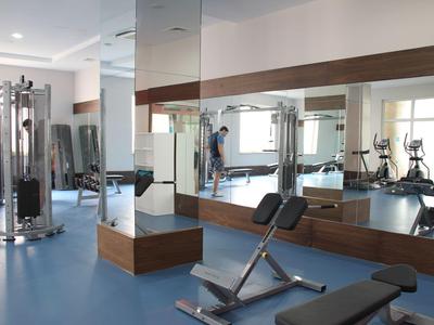 Moderní fitness s posilovacími stroji a velkými zrcadly v hotelu.