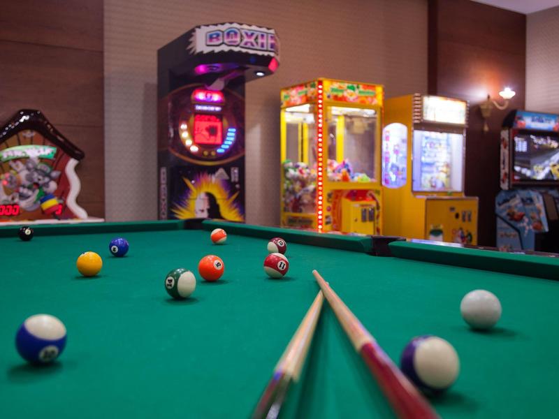 Stół bilardowy z kulami i kijem w pokoju z automatami do gier.